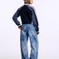 Modelo con jersey Pole Knit Navy de Cold Culture en vista posterior de tres cuartos, con mangas azul grisáceo, franjas blancas y espalda azul marino.