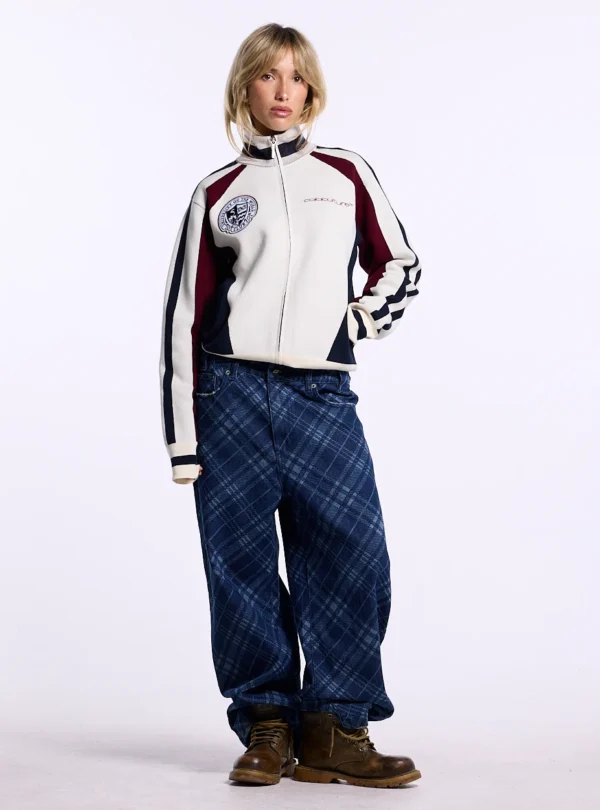 Modelo con jersey Pole Knit Off White de Cold Culture, con cuello alto, cremallera frontal, escudo en el pecho y mangas con franjas azul marino.