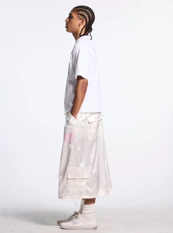 Vista lateral de modelo con Shorts Postal Capri de Cold Culture en color off-white, bolsillo cargo y emblema rosa