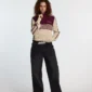 Modelo con jersey Powerline Zip Knit de Cold Culture en beige y burdeos, combinado con vaqueros negros anchos y cinturón de estrellas.