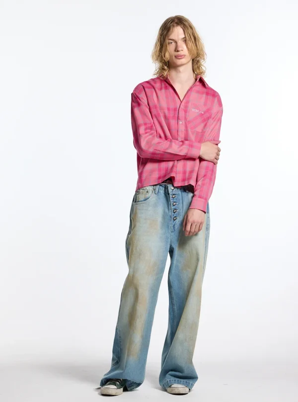 Modelo de cuerpo entero con camisa Rake rosa de cuadros de Cold Culture, combinada con vaqueros anchos de efecto desgastado y zapatillas