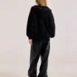 Modelo de espaldas con la sudadera Raw Zip-up Hoodie negra de Cold Culture, mostrando la capucha bajada con tachuelas metálicas y el corte holgado.