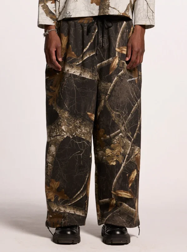 Modelo llevando los pantalones deportivos Cold Culture Realtree Black con estampado de camuflaje, vistos de frente