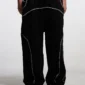 Detalle frontal del ajuste ancho de los pantalones deportivos negros Cold Culture Roller con costuras en contraste