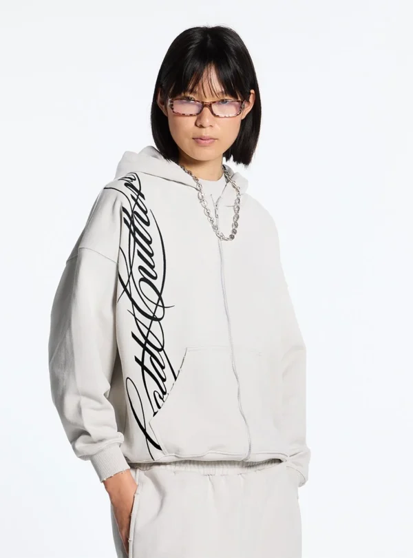 Cold Culture Script Sudadera Con Cremallera – Light Grey – Vista frontal en modelo Modelo con sudadera con cremallera Cold Culture Script en gris claro, con gráfico negro de estilo manuscrito en el lateral