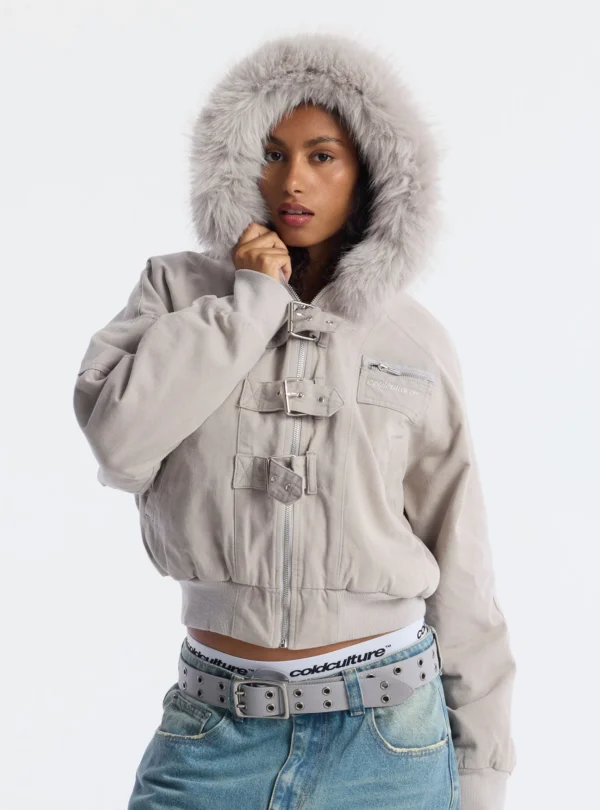 Cold Culture Shackle Bomber Off White – Detalle frontal con capucha Primer plano frontal del abrigo Cold Culture Shackle Bomber Off White con capucha de pelo, hebillas metálicas y bolsillo con cremallera en el pecho.