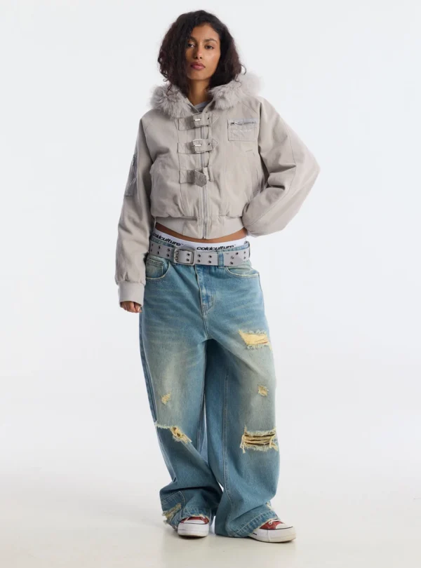 Cold Culture Shackle Bomber Off White – Vista frontal con modelo Modelo con el abrigo Cold Culture Shackle Bomber Off White, con cierre de cremallera, tres correas con hebillas y capucha con pelo.