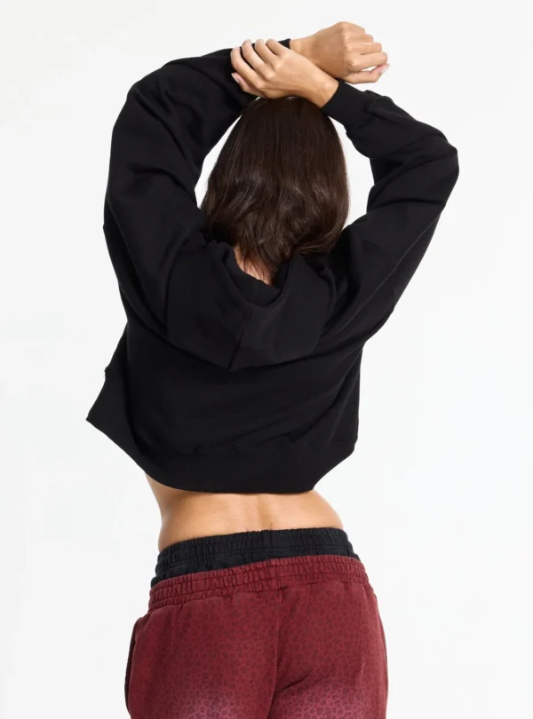 Modelo de espaldas con sudadera negra Shot de Cold Culture mostrando la capucha y el corte holgado