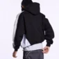 Vista trasera de la sudadera Speed Spoke de Cold Culture puesta en un modelo, con espalda negra, capucha y paneles grises y blancos en las mangas y laterales.