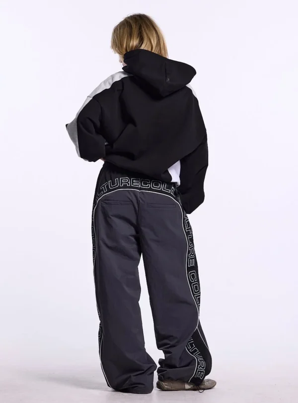 Modelo de cuerpo entero de espaldas con sudadera Speed Spoke de Cold Culture, de corte holgado, capucha negra y paneles grises en los hombros.