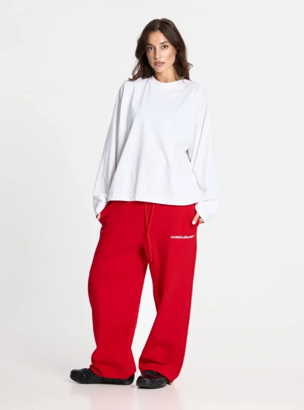 Modelo femenina con pantalones deportivos rojos Stars de Cold Culture, cintura con cordón, logotipo blanco y corte holgado de pernera ancha.