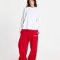 Modelo femenina con pantalones deportivos rojos Stars de Cold Culture, cintura con cordón, logotipo blanco y corte holgado de pernera ancha.