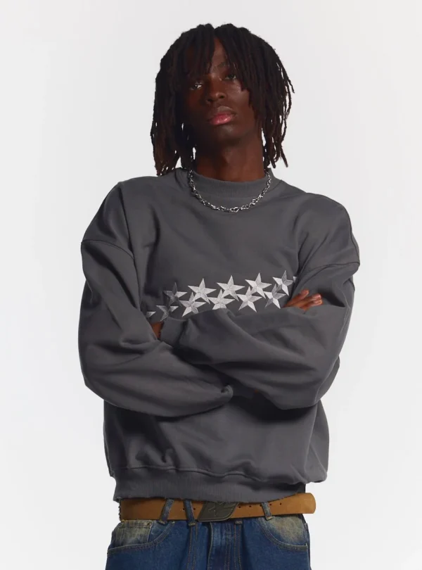 Modelo con sudadera sin capucha Cold Culture Stars en Dust Grey y diseño de estrellas bordadas en el pecho