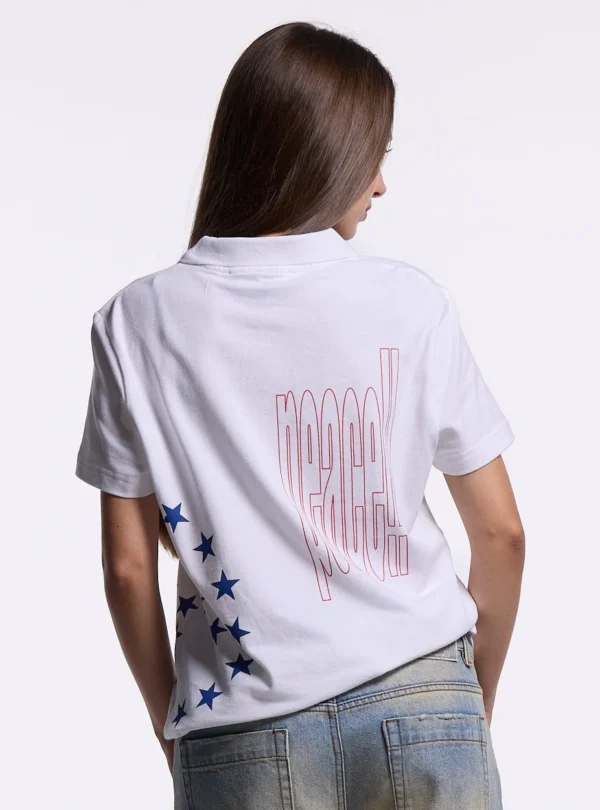Detalle de la espalda del polo blanco Starttrail de Cold Culture en modelo femenina, con gráfico Peace rojo y estampado de estrellas azules.
