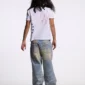 Modelo masculino de espaldas con polo blanco Starttrail de Cold Culture, gráfico Peace rojo y estrellas azules en el lateral.