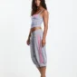 Modelo de perfil con el top de tirantes Strapline Tank Top Mujer de Cold Culture en gris jaspeado, con detalle rosa en el pecho.