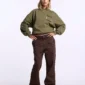 Modelo con pantalones Brown Cold Culture Strata V3 de frente, con pernera ancha, bolsillos cargo y hebillas en la cintura