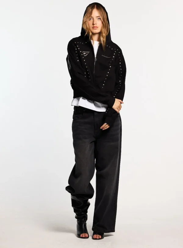 Modelo con sudadera con cremallera negra Cold Culture Stud, capucha puesta y detalles de tachuelas metálicas