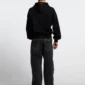 Modelo de espaldas con pantalones Cold Culture Studs en denim negro, bolsillos con tachuelas y bordado COLD