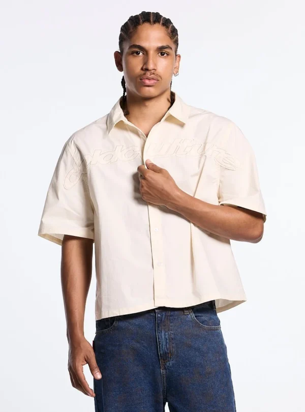 Vista frontal de un modelo con la camisa Sun Distress beige de Cold Culture, mostrando el logotipo de contorno a tono sobre el pecho