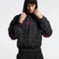 Modelo con sudadera negra Tartan de Cold Culture a cuadros, capucha puesta, logo rojo y bolsillo canguro