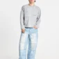 Modelo con pantalones Vera Loose Light Blue de Cold Culture, de corte holgado y perneras anchas, combinados con una sudadera gris y zapatillas blancas.
