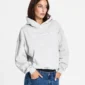 Modelo con sudadera Vertical Heather Grey de Cold Culture, capucha bajada, corte holgado, bolsillo canguro y gráficos blancos en el pecho.