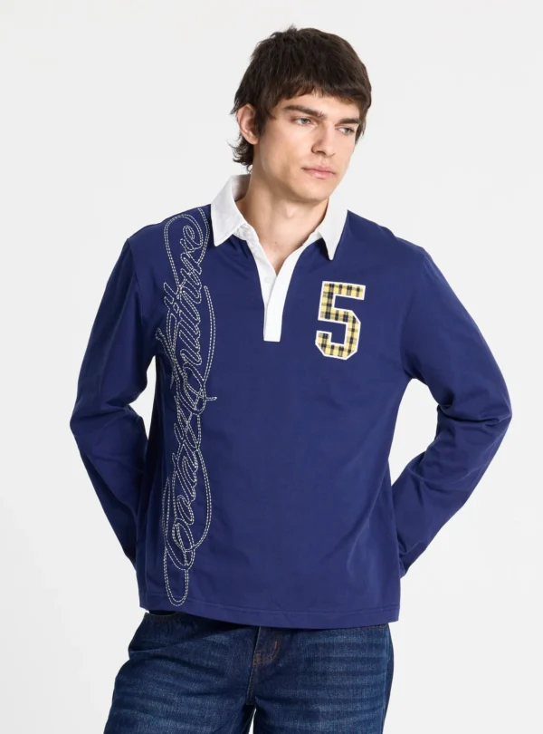 Detalle frontal del polo Windsor Longsleeve Polo Navy de Cold Culture, con cuello blanco, bordado vertical de la marca y parche del número 5 de cuadros.